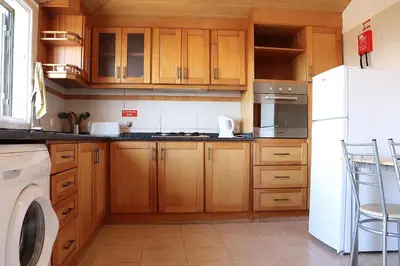 a kitchen with wooden cabinets and a white refrigerator at Casa Bela Vista in Ribeira Brava