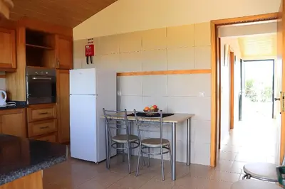 a kitchen with a white refrigerator and a counter with stools at Casa Bela Vista in Ribeira Brava
