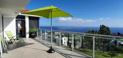 a green umbrella on the balcony of a house at Apartamento Doreen in Caniço