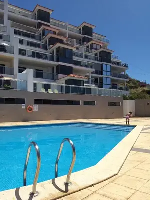 a swimming pool in front of a large building at Apartamento Doreen in Caniço