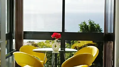 a table and yellow chairs in front of a window at Apartamento Doreen in Caniço