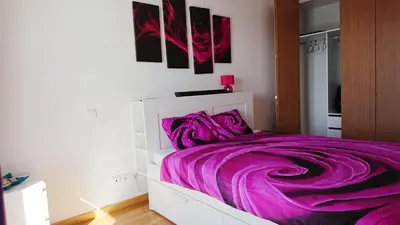 a white bed with purple sheets in a bedroom at Apartamento Doreen in Caniço