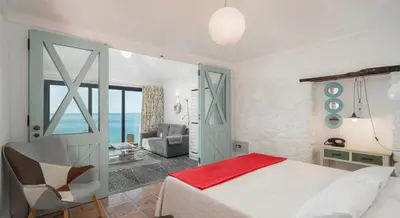 a bedroom with a bed and a chair at OurMadeira - Cottage do Mar in Arco da Calheta