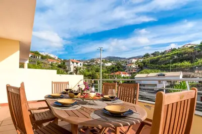 a wooden table and chairs on a balcony with a view at Apartamento Serramar , Vistas deslumbrantes in Calheta