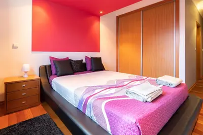 a bedroom with a large bed with a pink wall at Apartamento Serramar , Vistas deslumbrantes in Calheta
