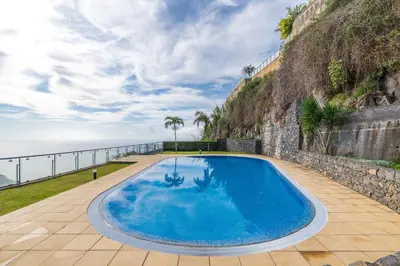 a large blue swimming pool next to the ocean at Apartamento Serramar , Vistas deslumbrantes in Calheta
