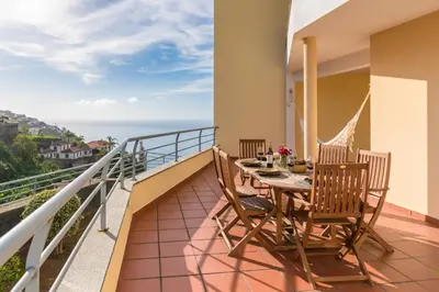 a balcony with a table and chairs and the ocean at Apartamento Serramar , Vistas deslumbrantes in Calheta