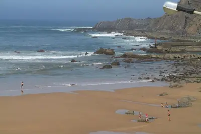 a group of people standing on a beach near the ocean at Villa Bartoni in Aljezur