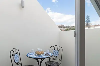 a small table with two chairs and a table with food on a balcony at Downtown Funchal Apartments by An Island Apart in Funchal