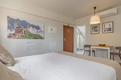 a bedroom with a bed and a table with chairs at Downtown Funchal Apartments by An Island Apart in Funchal