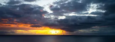 a cloudy sky with the sun in the middle of the ocean at Shearwaters - Sounds of the sea in Funchal