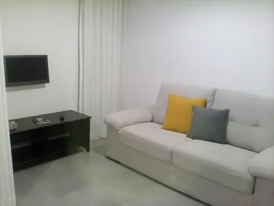 a living room with a white couch with two pillows at Shearwaters - Sounds of the sea in Funchal
