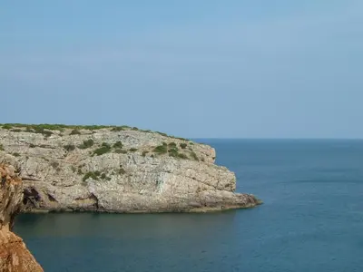 a rock cliff with the ocean in the background at Casa Luana - Rooms in Sagres