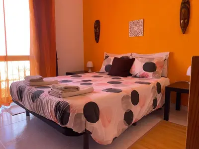 a bedroom with a large bed with orange walls at Casa Luana - Rooms in Sagres