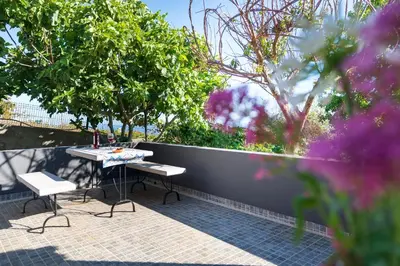 a table and chairs on a patio next to a fence at Casa da Mãe do Raivinha in Arco da Calheta