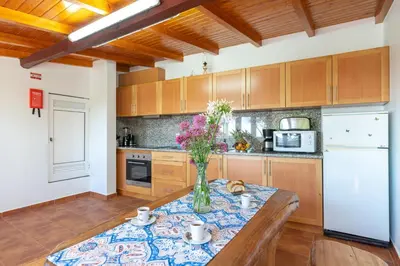 a kitchen with a table with a vase of flowers on it at Casa da Mãe do Raivinha in Arco da Calheta