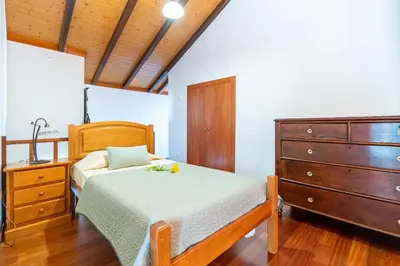 a bedroom with a bed and a dresser at Casa da Mãe do Raivinha in Arco da Calheta