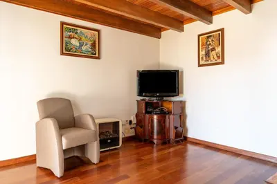 a living room with a chair and a flat screen tv at Casa da Mãe do Raivinha in Arco da Calheta