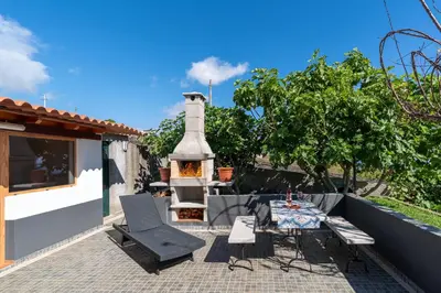 a patio with a fireplace and a table and chairs at Casa da Mãe do Raivinha in Arco da Calheta
