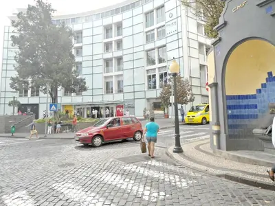 a man walking down a street next to a red car at Terrace Apartment in Funchal