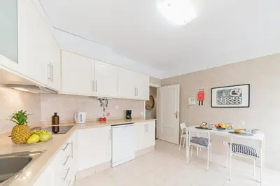 a kitchen with white cabinets and a table and chairs at Arrifes I by An Island Apart in Funchal