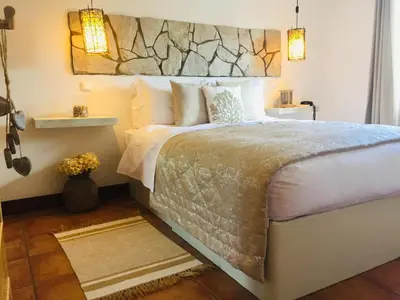 a bedroom with a large bed with a stone headboard at Herdade Monte Do Sol in Aljezur