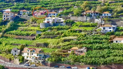 a house on a hill with a red circle on it at Pink House in Ponta do Sol