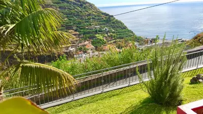 a view of a hill with the ocean in the background at Pink House in Ponta do Sol