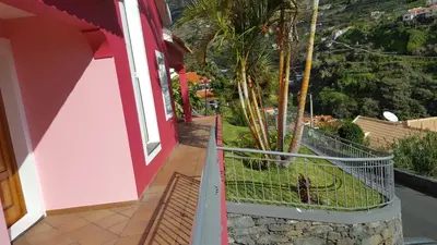 a balcony of a house with a bird in a cage at Pink House in Ponta do Sol