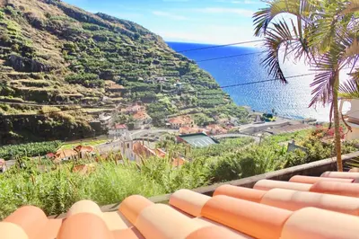 a view of a hill with the ocean in the background at Pink House in Ponta do Sol