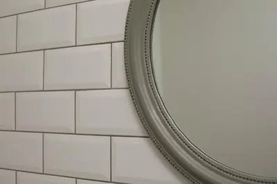 a mirror on a bathroom wall with white tiles at Ivens Residence in Funchal