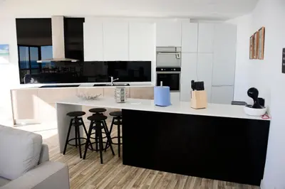 a kitchen with a black and white counter and stools at Luz Beach Rooftop Penthouse in Luz