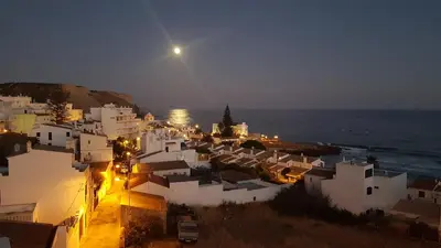 a view of a town at night with the ocean at Luz Beach Rooftop Penthouse in Luz