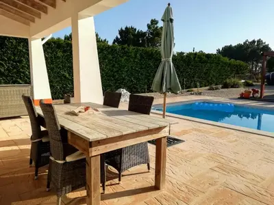 a wooden table and umbrella next to a swimming pool at Casa Guna in Aljezur