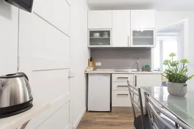 a kitchen with white cabinets and a table at Rochinha Cozy Home in Funchal