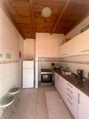 a kitchen with a white refrigerator and two stools in it at The Hill View House in Funchal