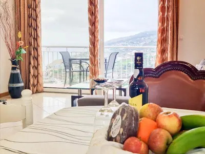 a table with a bottle of wine and fruit on it at Loreto Rose, Panoramic Ocean and Mountain View in Arco da Calheta