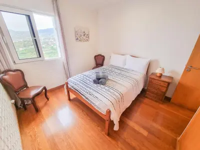 a bedroom with a bed with a table and a window at Loreto Rose, Panoramic Ocean and Mountain View in Arco da Calheta