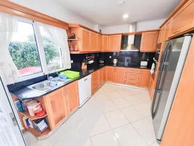a kitchen with wooden cabinets and a sink and a window at Loreto Rose, Panoramic Ocean and Mountain View in Arco da Calheta