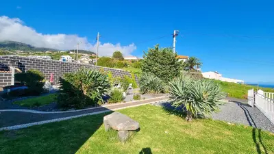 a garden with a bench in the grass at Loreto Rose, Panoramic Ocean and Mountain View in Arco da Calheta