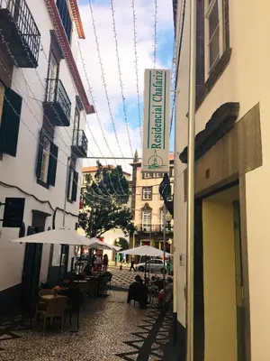a street with tables and umbrellas and a building at Residencial Chafariz /Queimada in Funchal