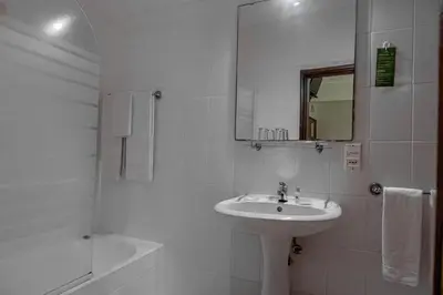 a white bathroom with a sink and a mirror at Residencial Chafariz /Queimada in Funchal