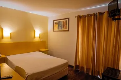 a hotel room with a bed and yellow curtains at Residencial Chafariz /Queimada in Funchal