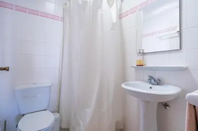a white bathroom with a toilet and a sink at Sea View - By WeHost in Câmara de Lobos