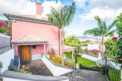 a pink house with palm trees at Vila Botânica - By WeHost in Funchal