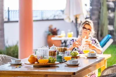 a woman sitting at a table with food and orange juice at Vila Botânica - By WeHost in Funchal