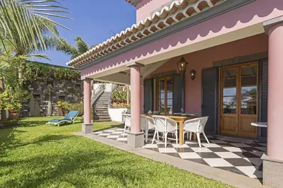 a patio with a table and chairs on a lawn at Vila Botânica - By WeHost in Funchal