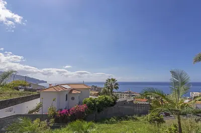 a view of a house with the ocean in the background at Vila Botânica - By WeHost in Funchal