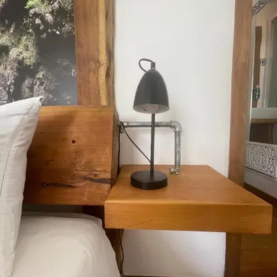 a lamp on a wooden table next to a bed at Modern & Recycled Guest House in Machico