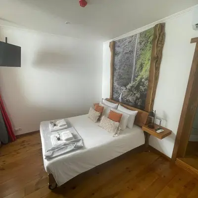 a bedroom with a white bed with a picture on the wall at Modern & Recycled Guest House in Machico
